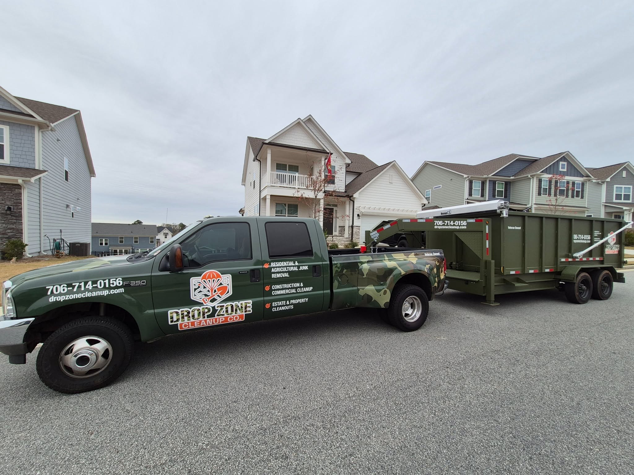 Drop Zone Cleanup Co. camo truck and dumpster trailer on-site in a Georgia neighborhood